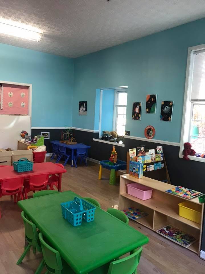 Classroom with colorful tables and chairs, bookshelves, and artwork on walls