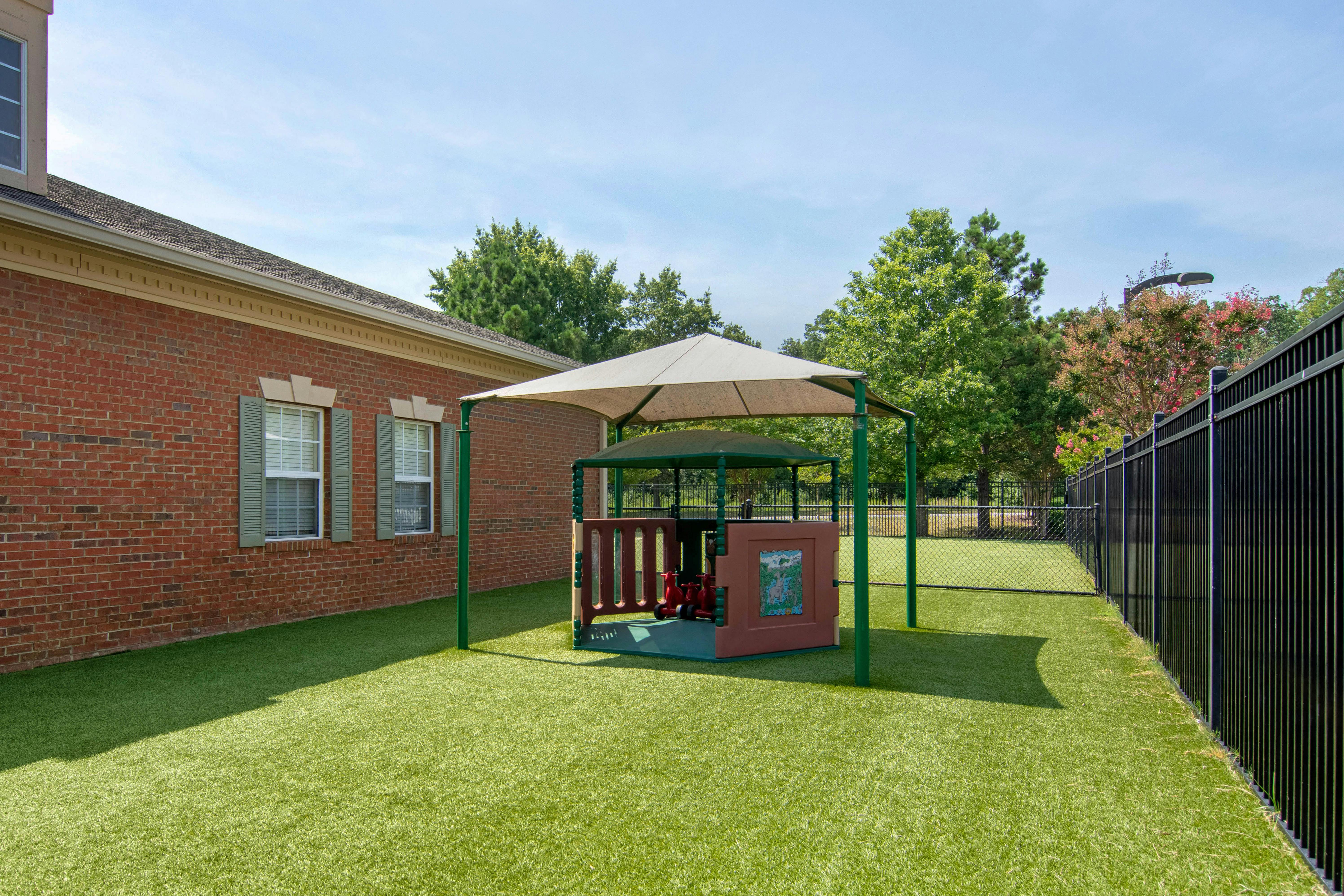 Playground area with artificial turf, covered play structure, brick building