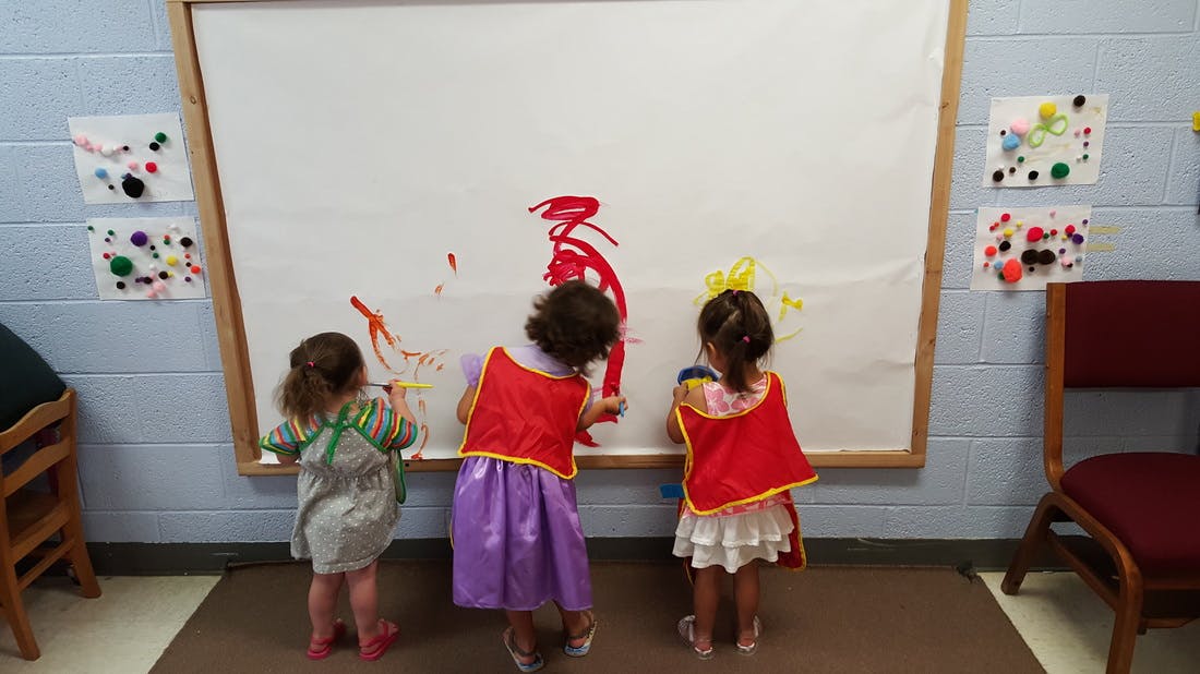 Three children painting on a large white board