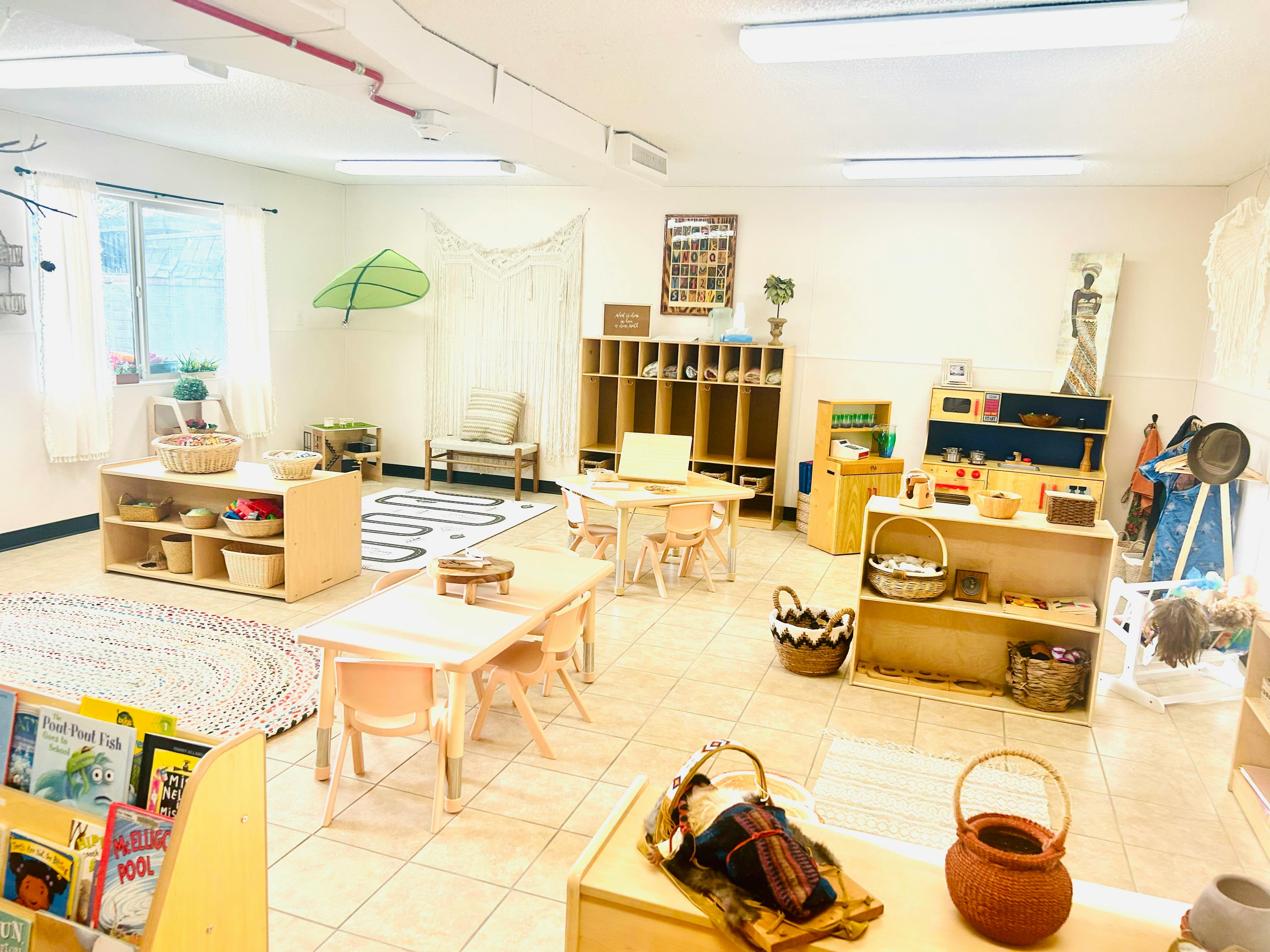 Classroom with small tables and chairs, shelves with baskets and learning materials