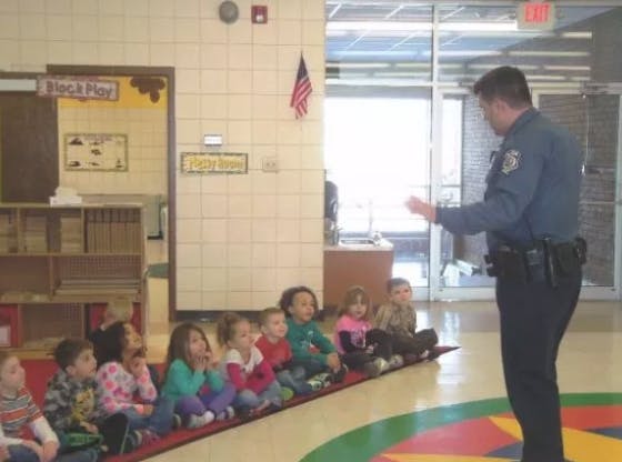 Police officer speaking to a group of children sitting on the floor