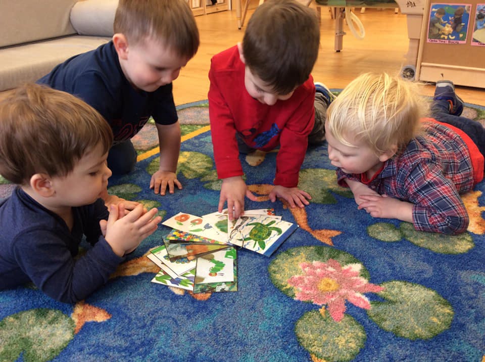 Four children on a rug looking at cards