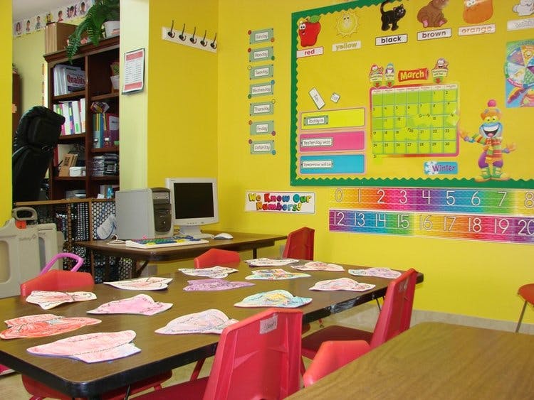 Classroom with tables, chairs, and a bulletin board with a calendar