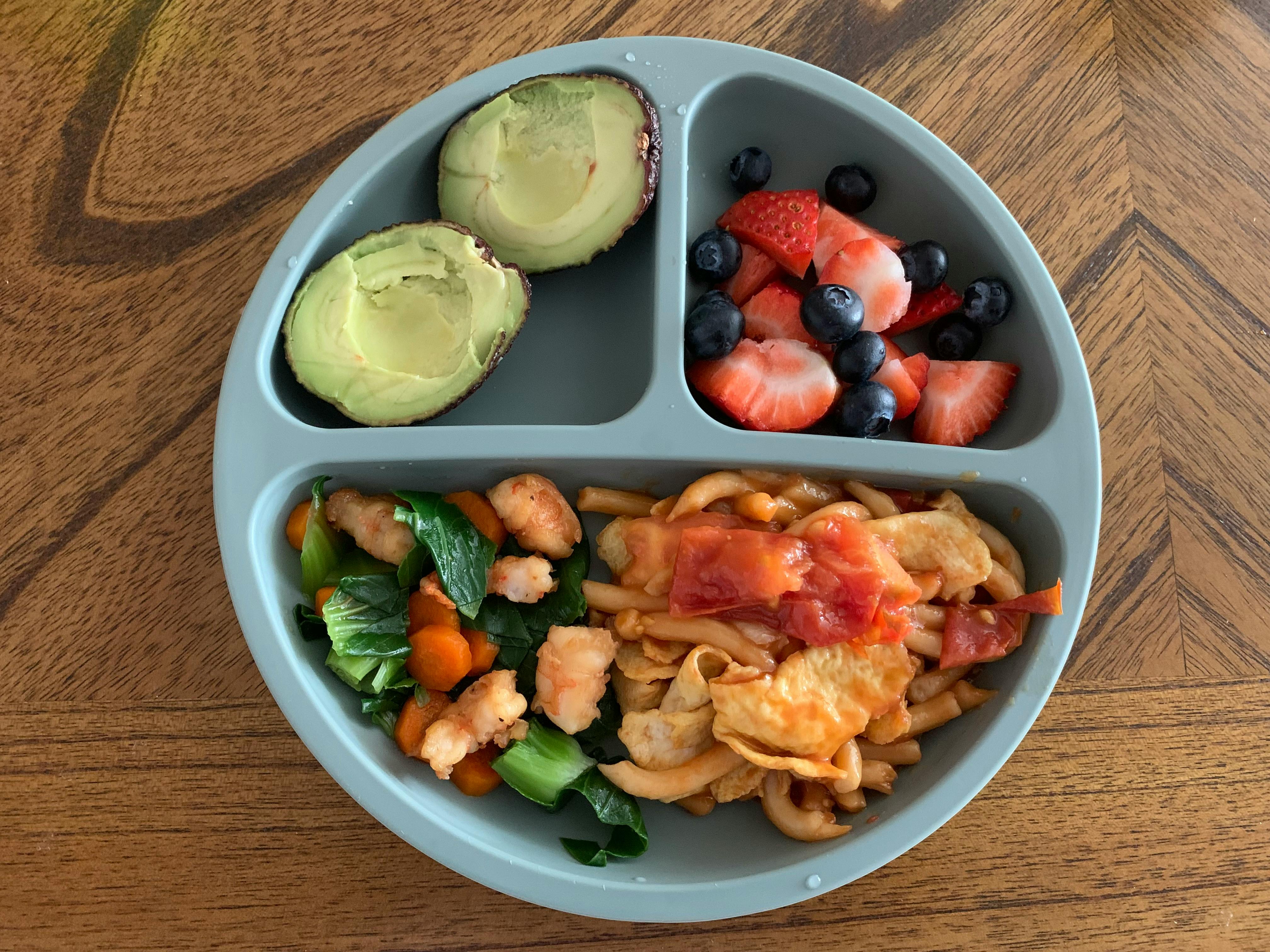 Divided plate with avocado, berries, vegetables with chicken, and pasta with sauce