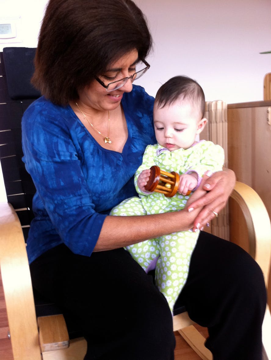 Person holding a child who is holding a wooden toy