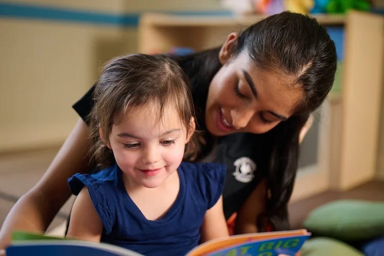 Person and child reading a book together