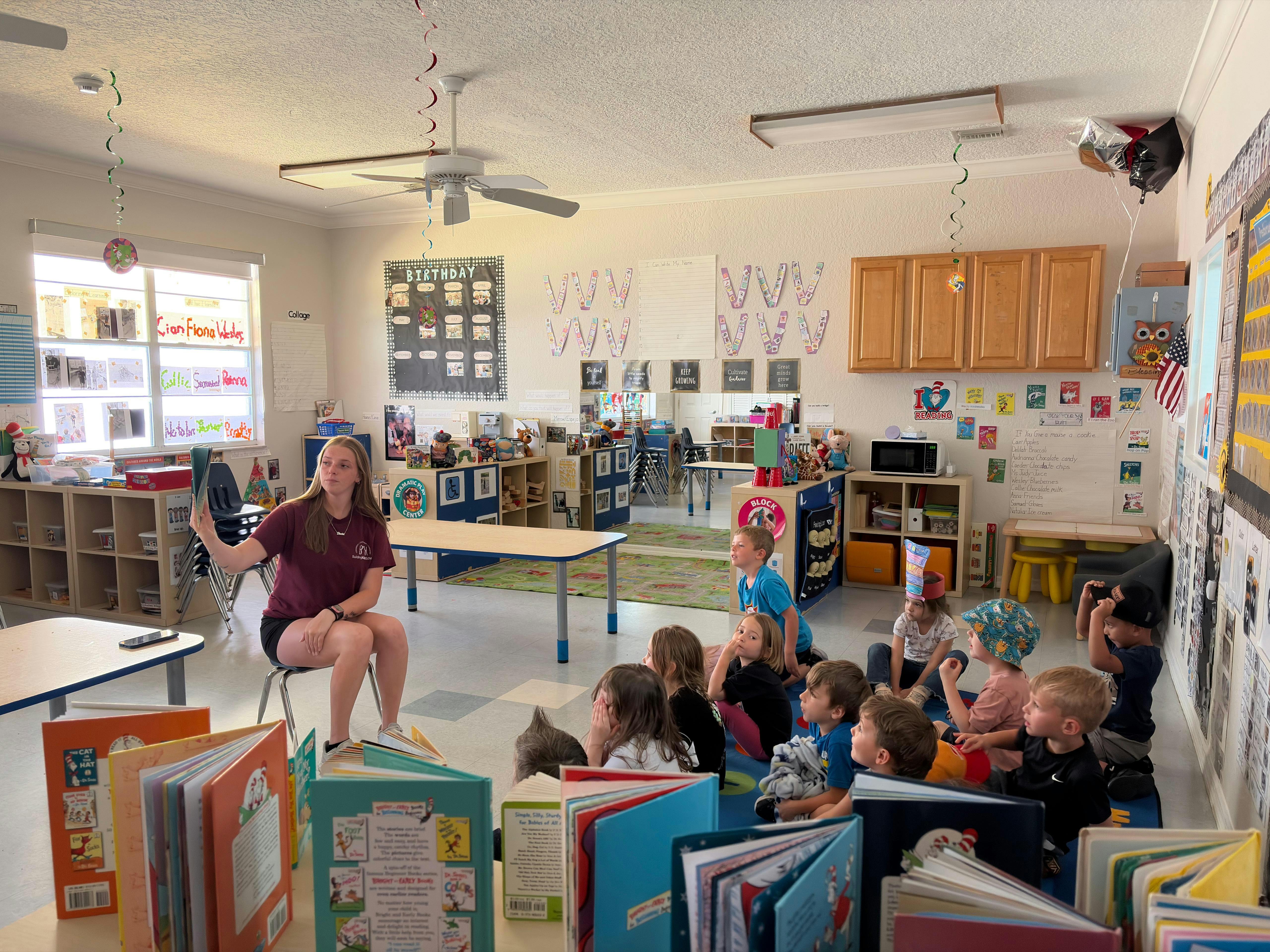 A person reading a book to a group of children sitting in a classroom