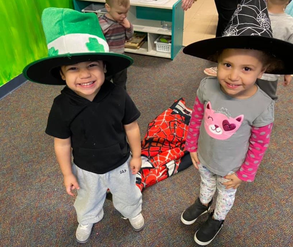 Two children wearing hats, one green and one black