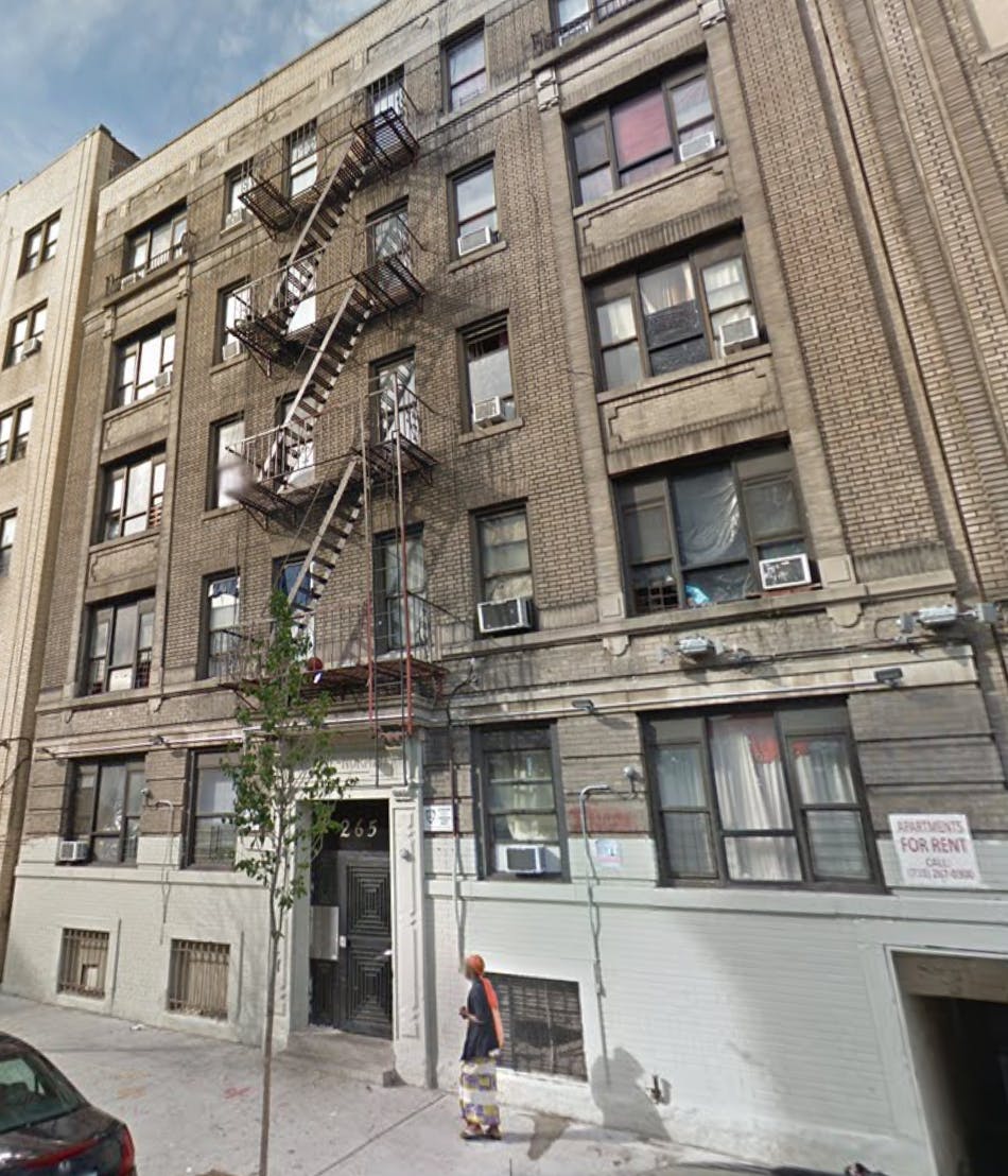 Brick apartment building with fire escapes and a person on the sidewalk