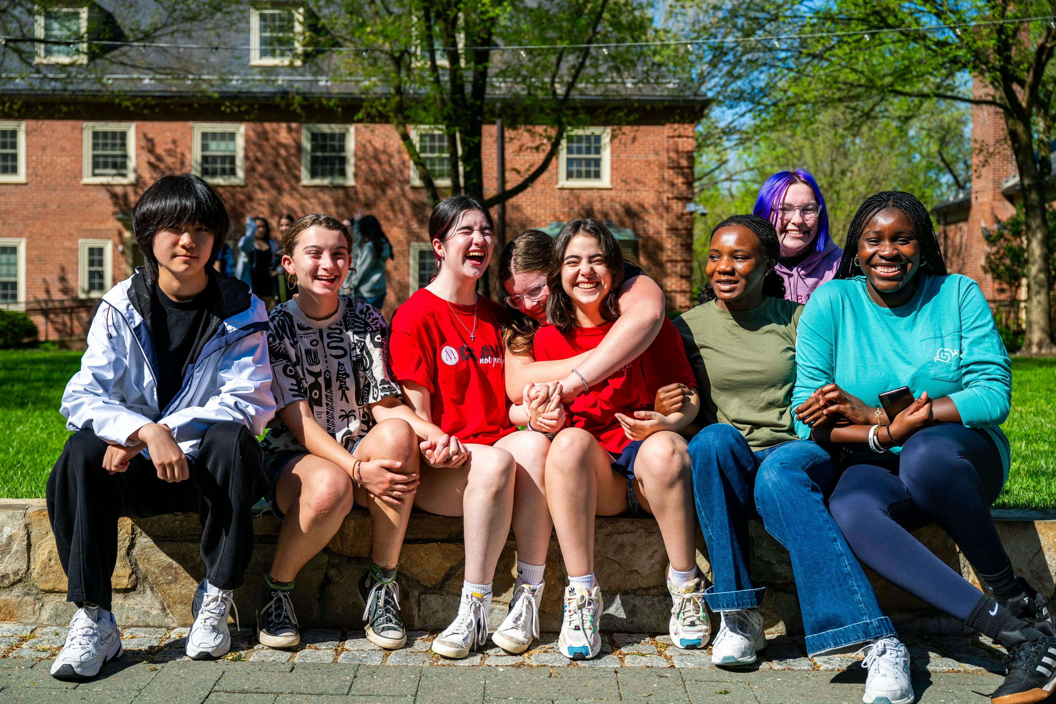 Group of young people sitting outdoors, some laughing
