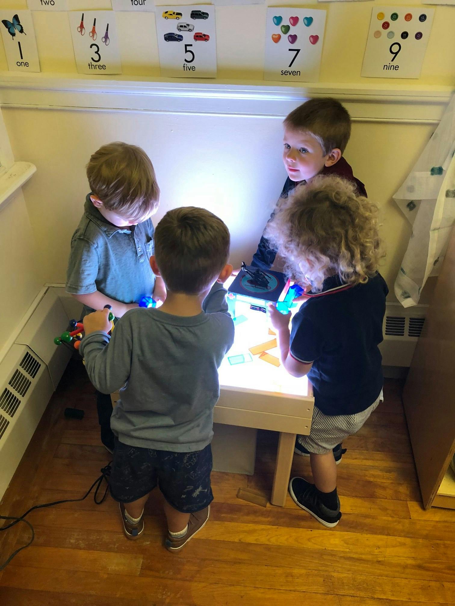 Four children playing around a light table