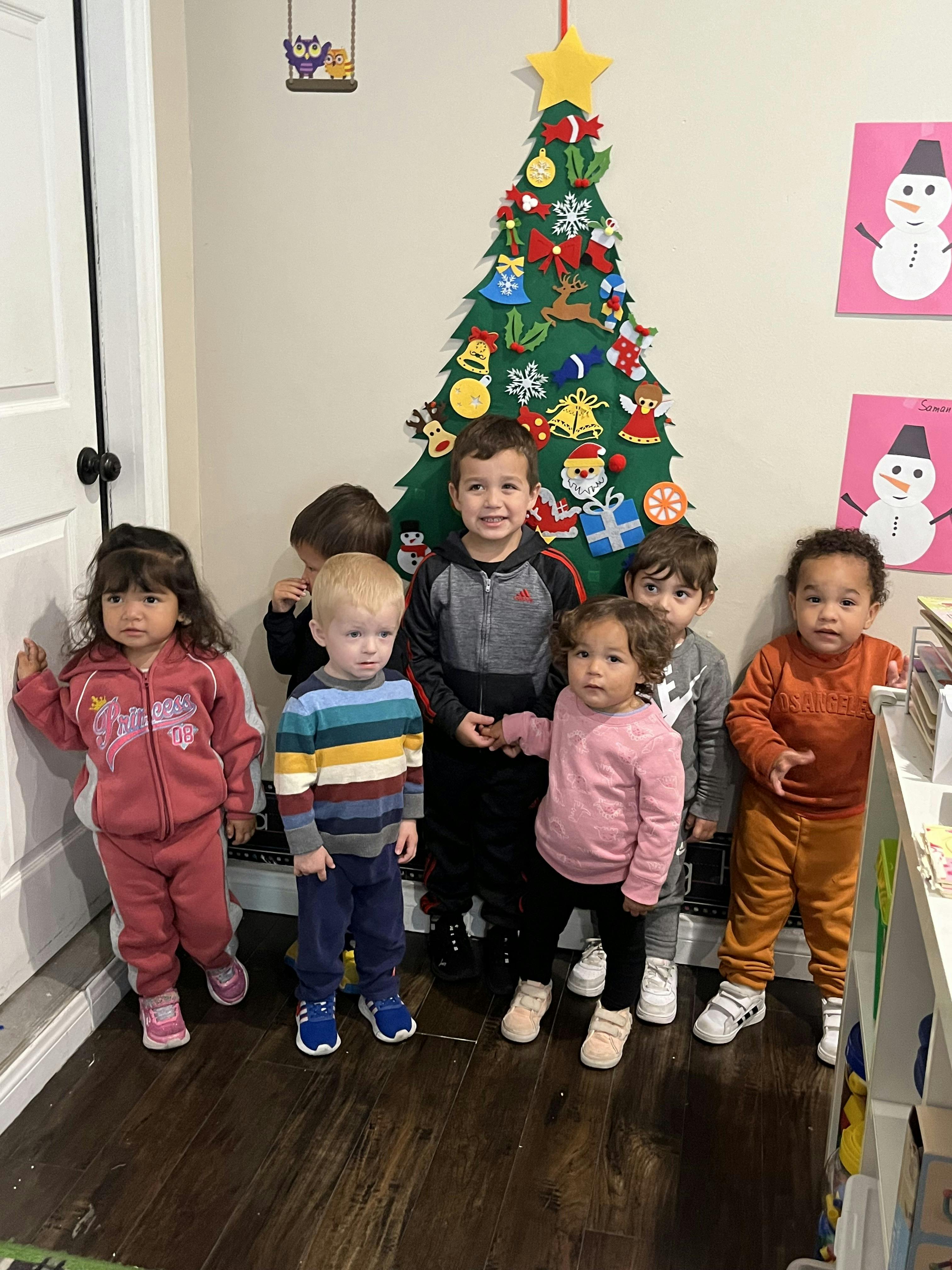 Group of children standing in front of a felt Christmas tree