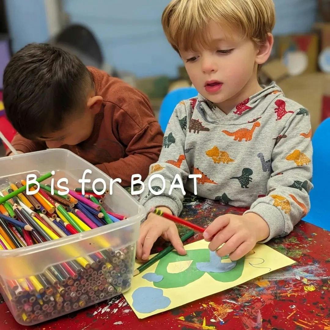 Child coloring a letter B on paper with another child nearby