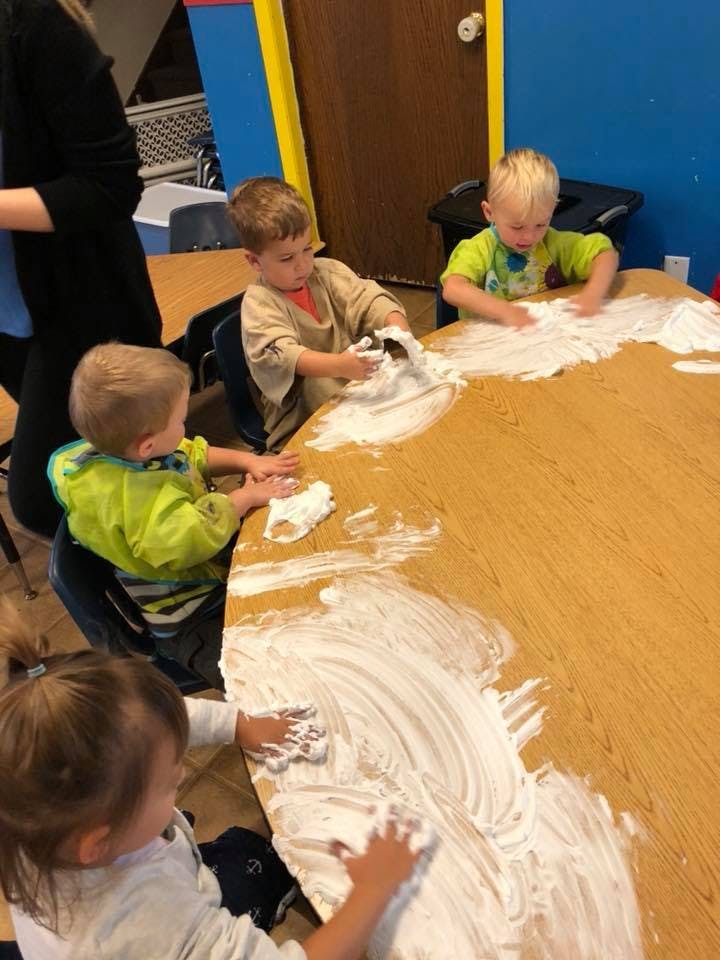 Children playing with shaving cream on a table