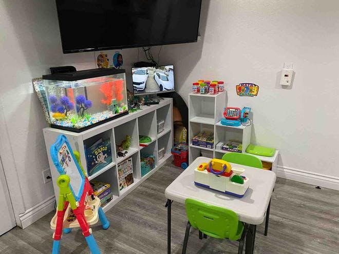 Playroom with a fish tank, shelves of toys, and a small table with chairs