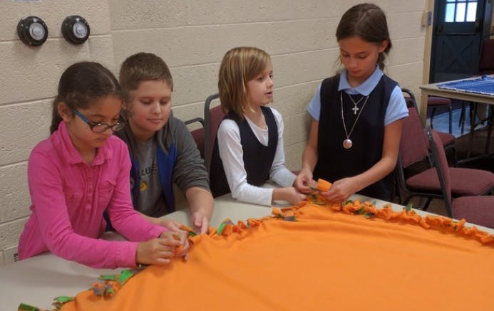 Four children making a blanket
