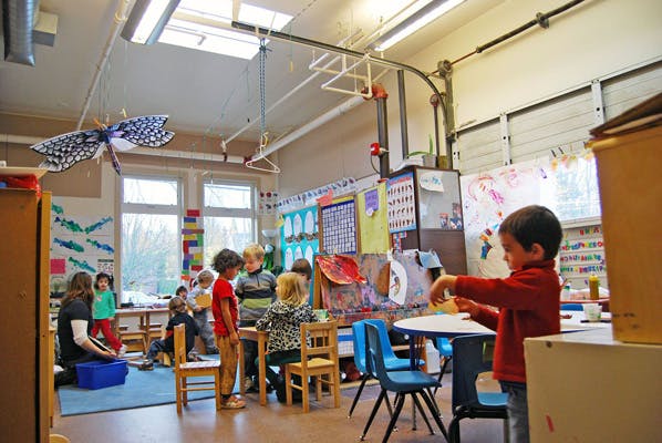 Teacher and children in a classroom with art on the walls