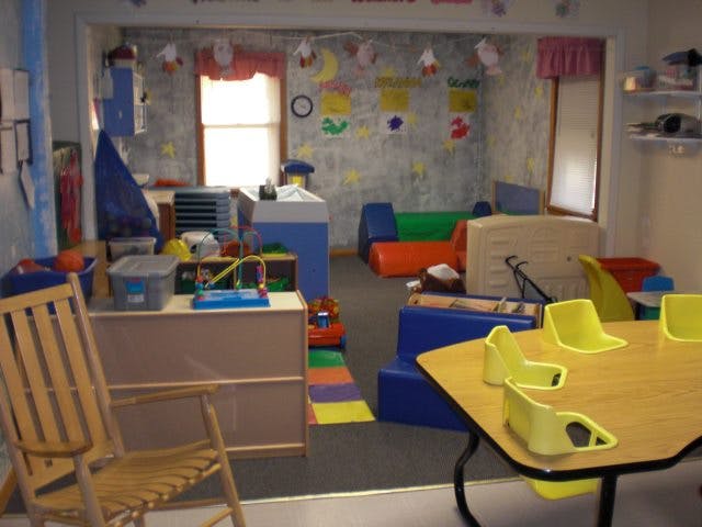 Playroom with small tables and chairs, soft play equipment, and toys