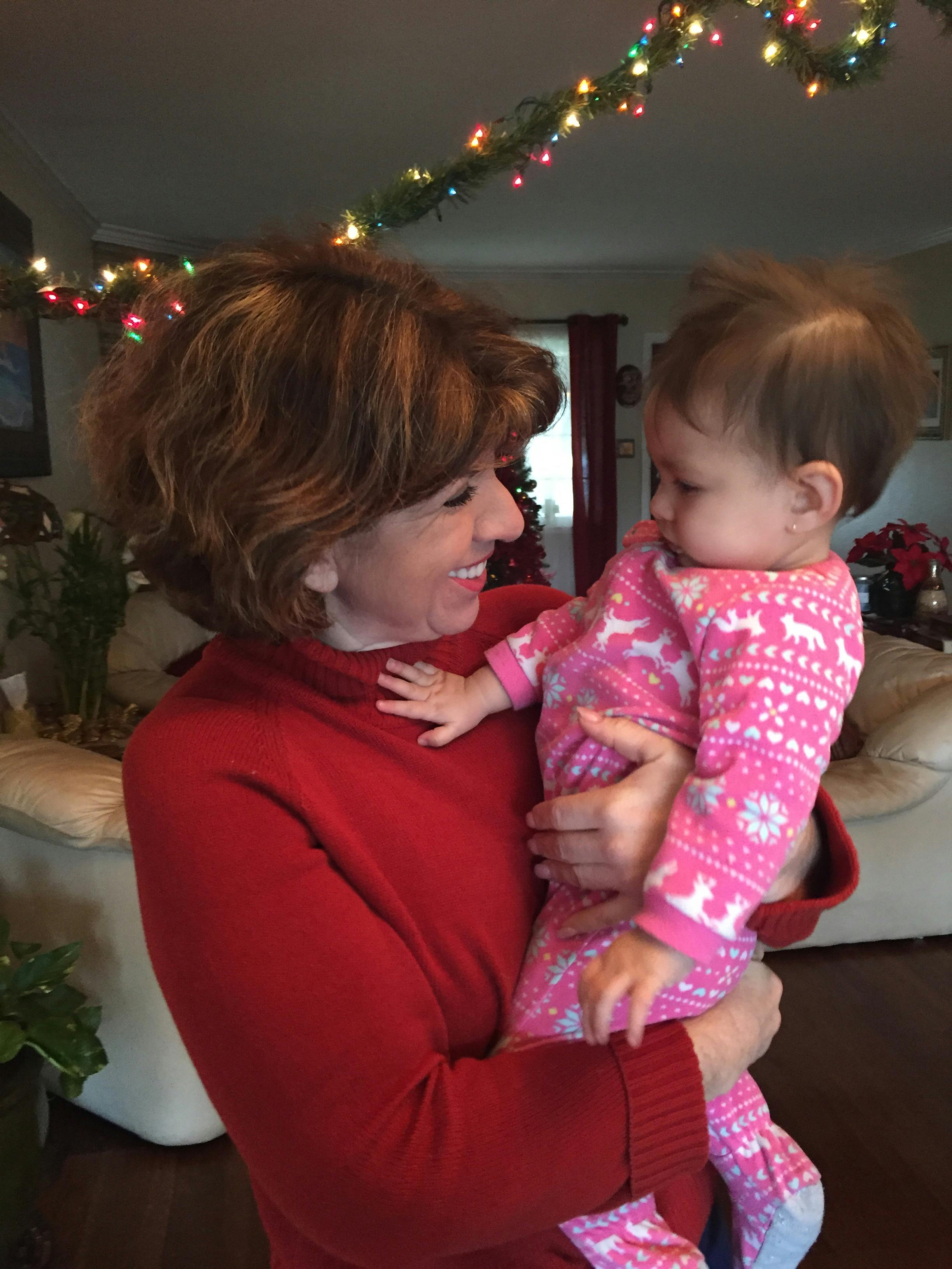 Person in red sweater holding a child in pink pajamas