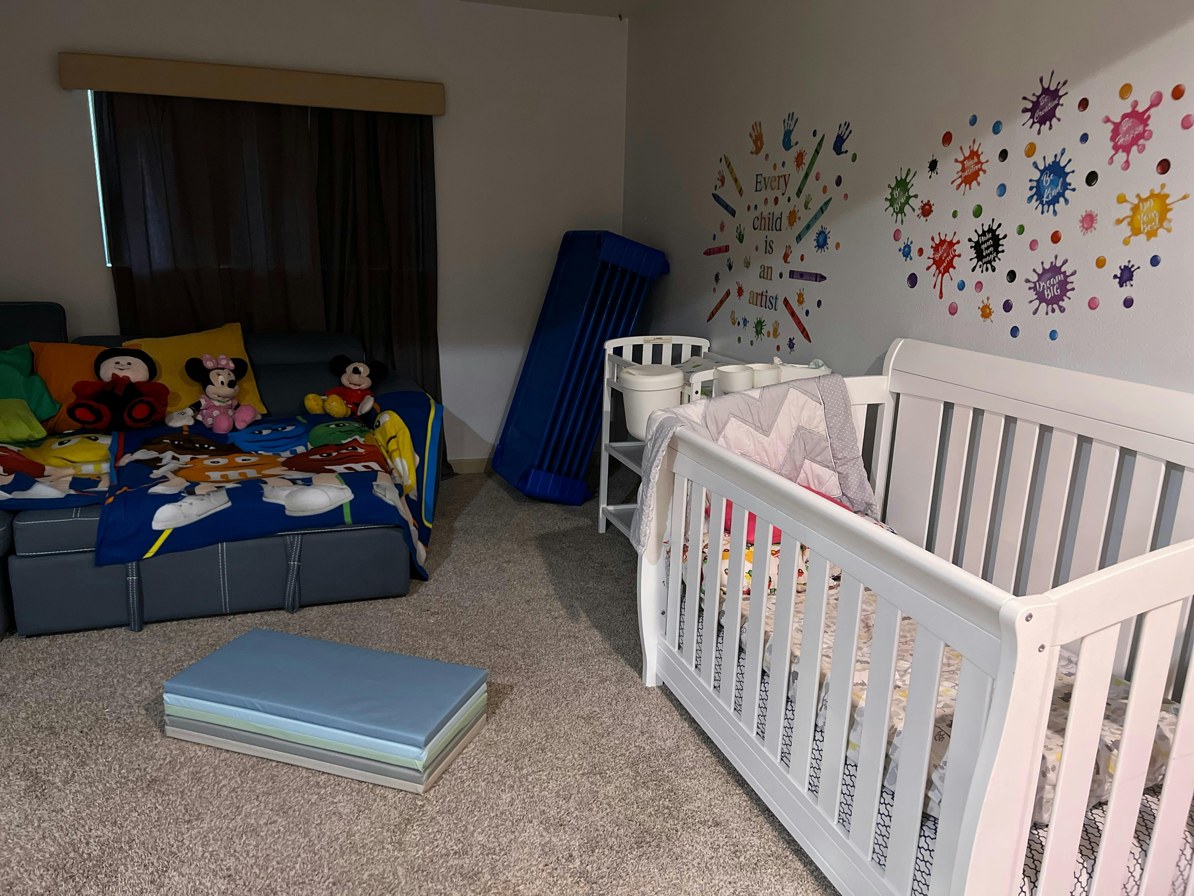 Child's room with a crib, sofa, and colorful wall decals