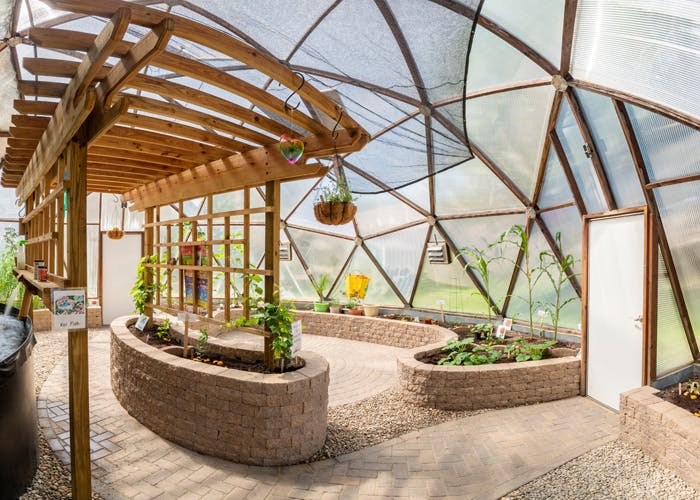 Interior of a geodesic dome greenhouse with plants in raised beds
