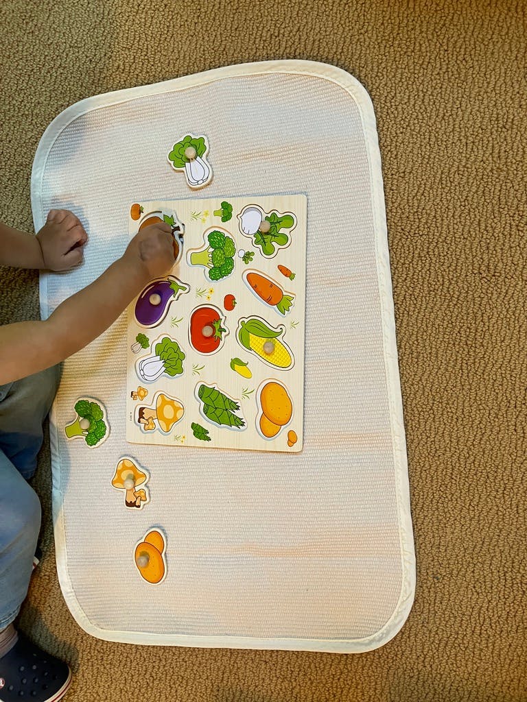 Child playing with a vegetable puzzle on a mat