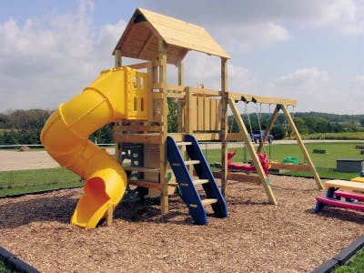 Wooden playground with yellow slide, blue ladder, and swings