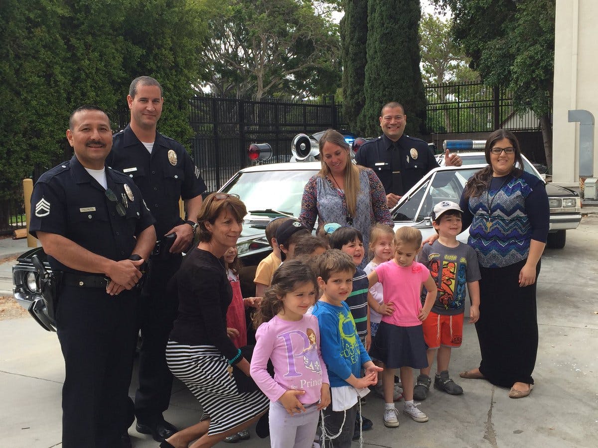 Police officers, adults, and children posing in front of a police car