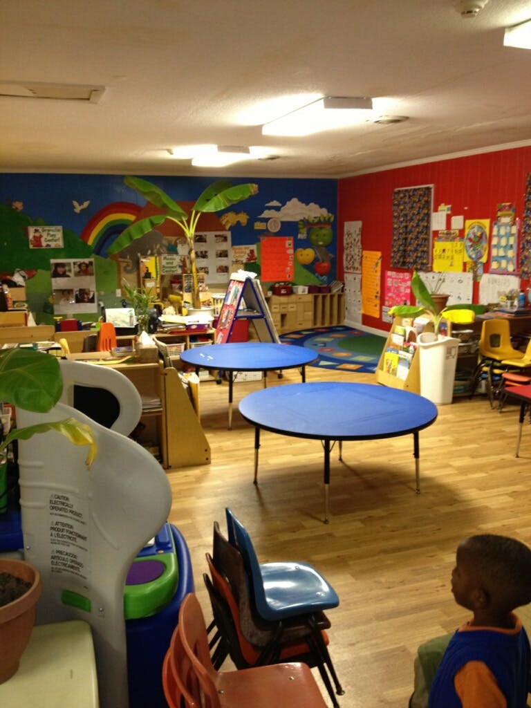 Child in a classroom with blue tables and colorful wall decorations