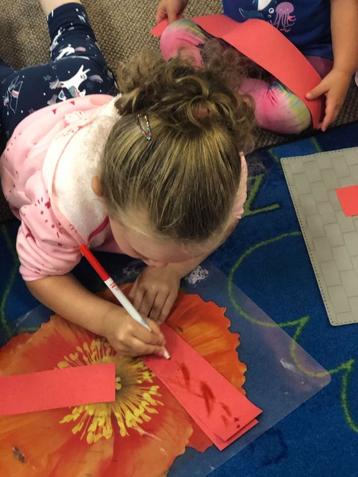 Child drawing on red paper with a marker