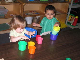 Two children playing with colorful cups and buckets