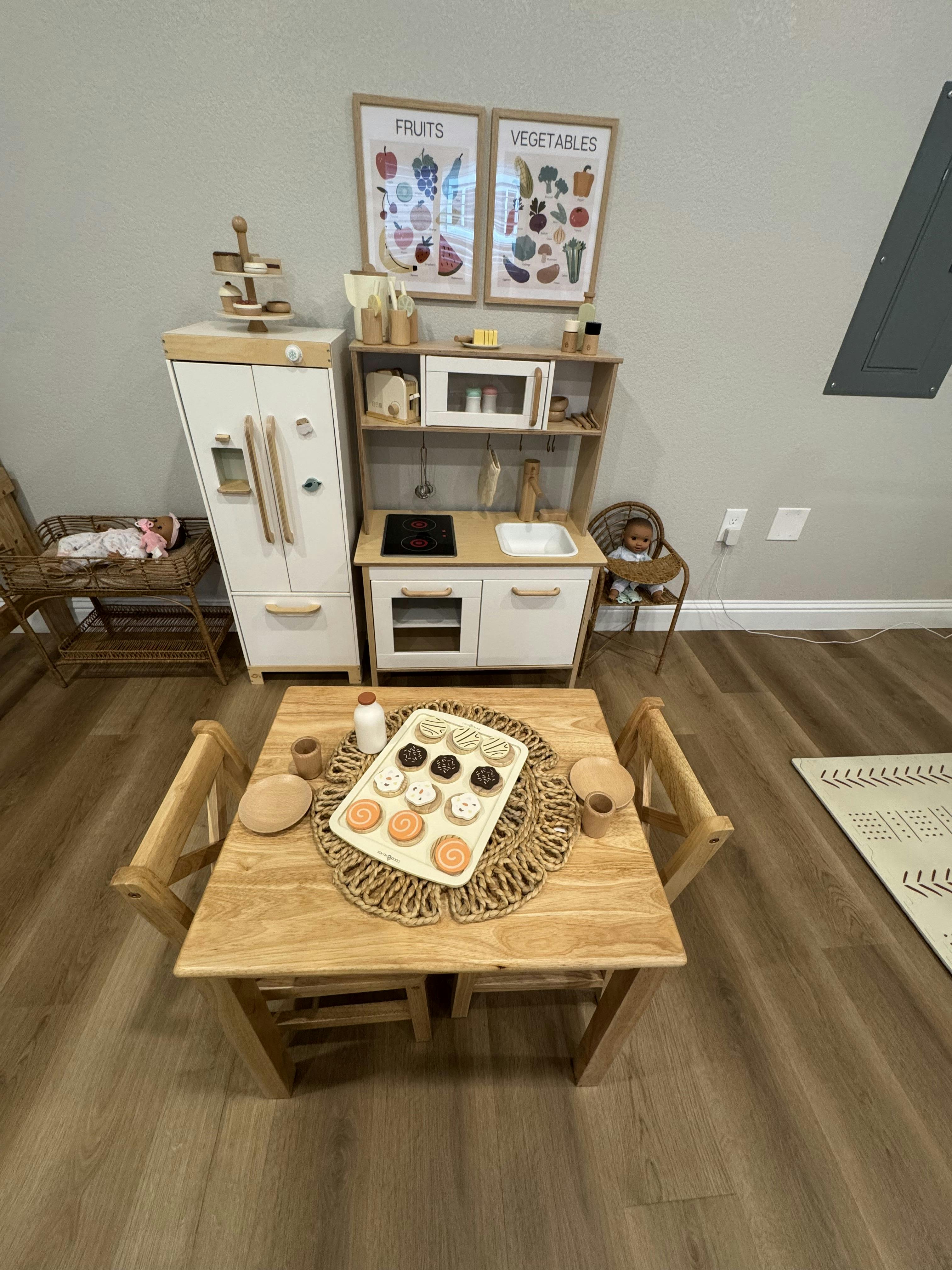 Play kitchen set with a small table and chairs, and a tray of toy cupcakes