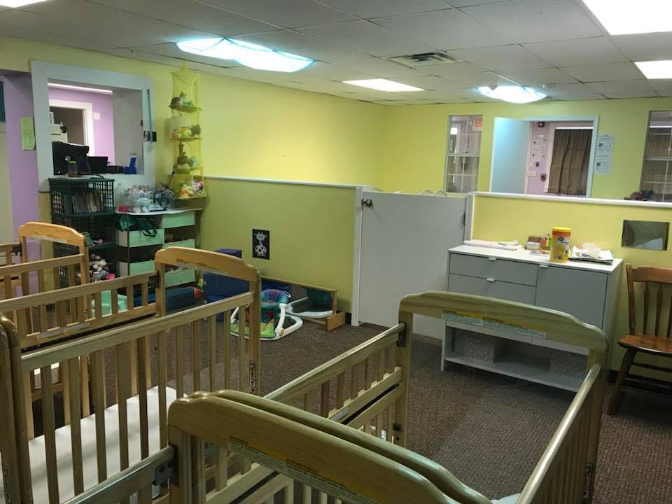Multiple cribs in a room with yellow walls