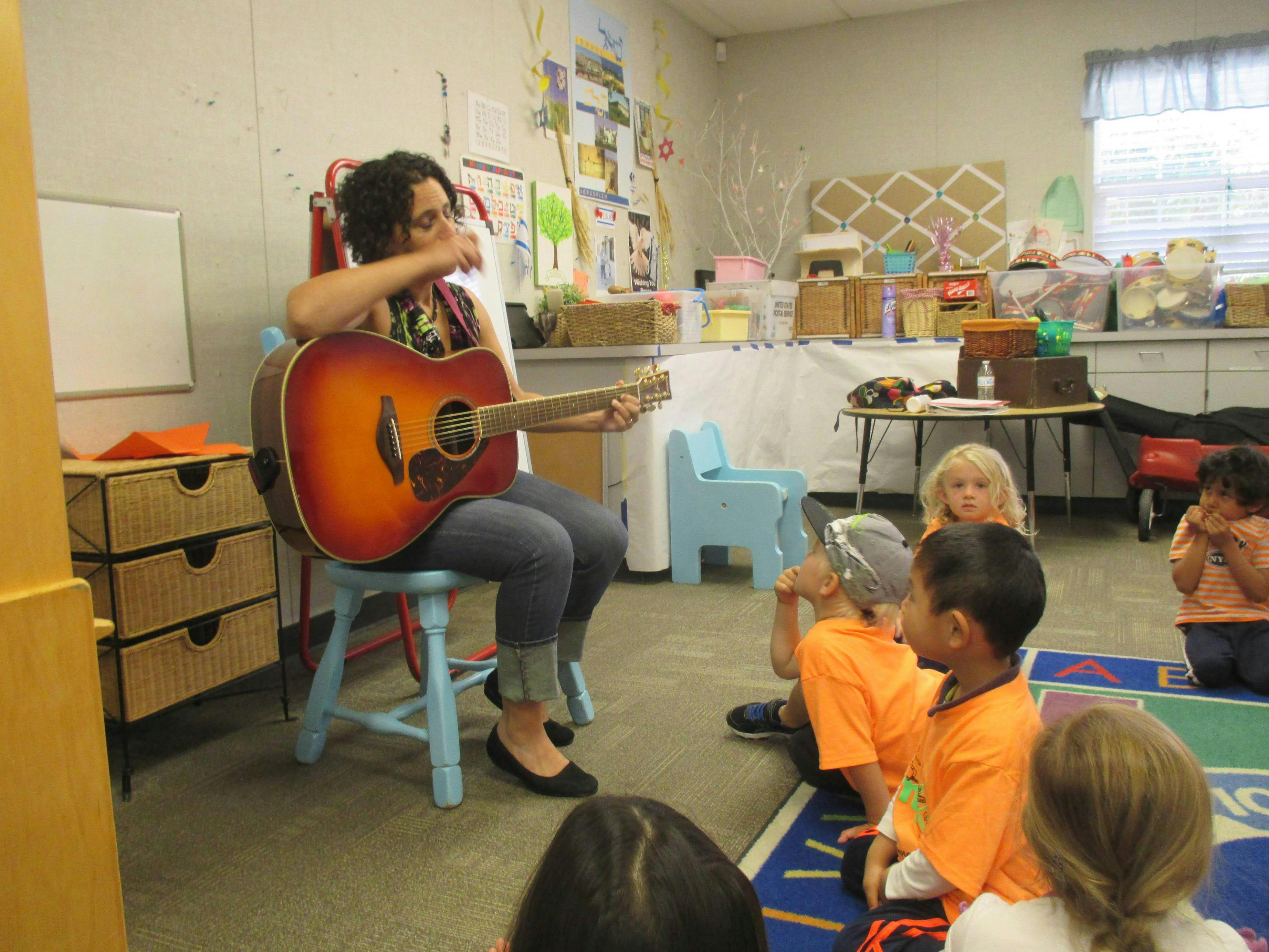 Person playing guitar for children in a classroom