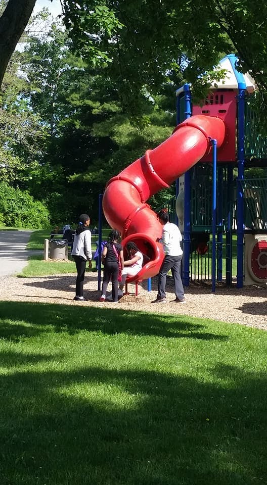 People and a child on a red playground slide