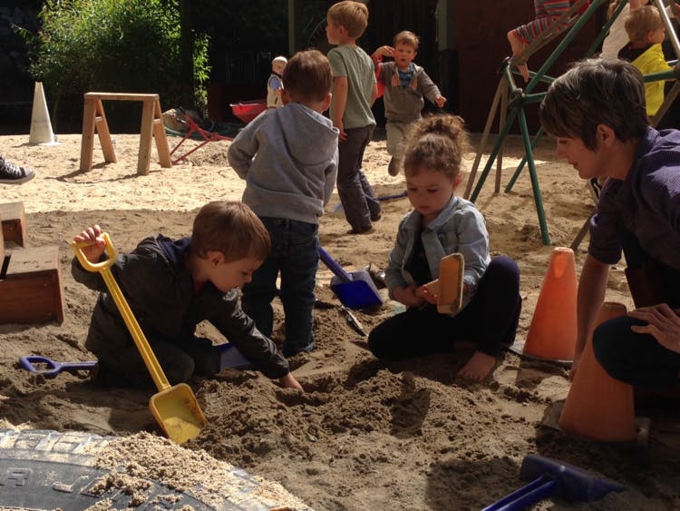Children playing in a sandbox with shovels