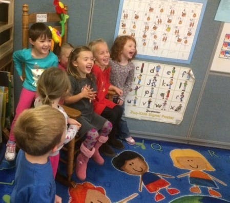 Group of children in a classroom looking at something off-camera