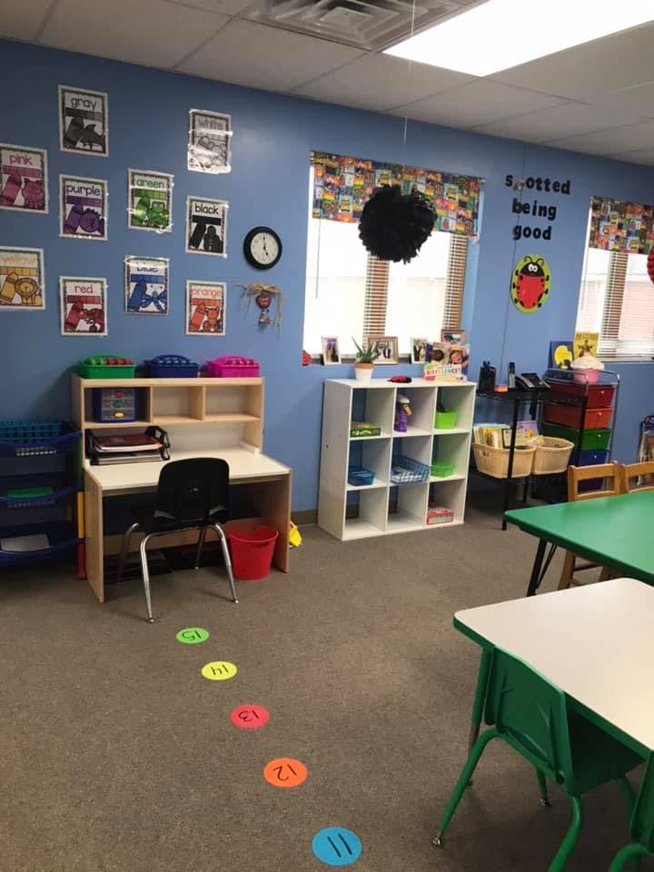 Classroom with a desk, shelves, and colorful floor markers