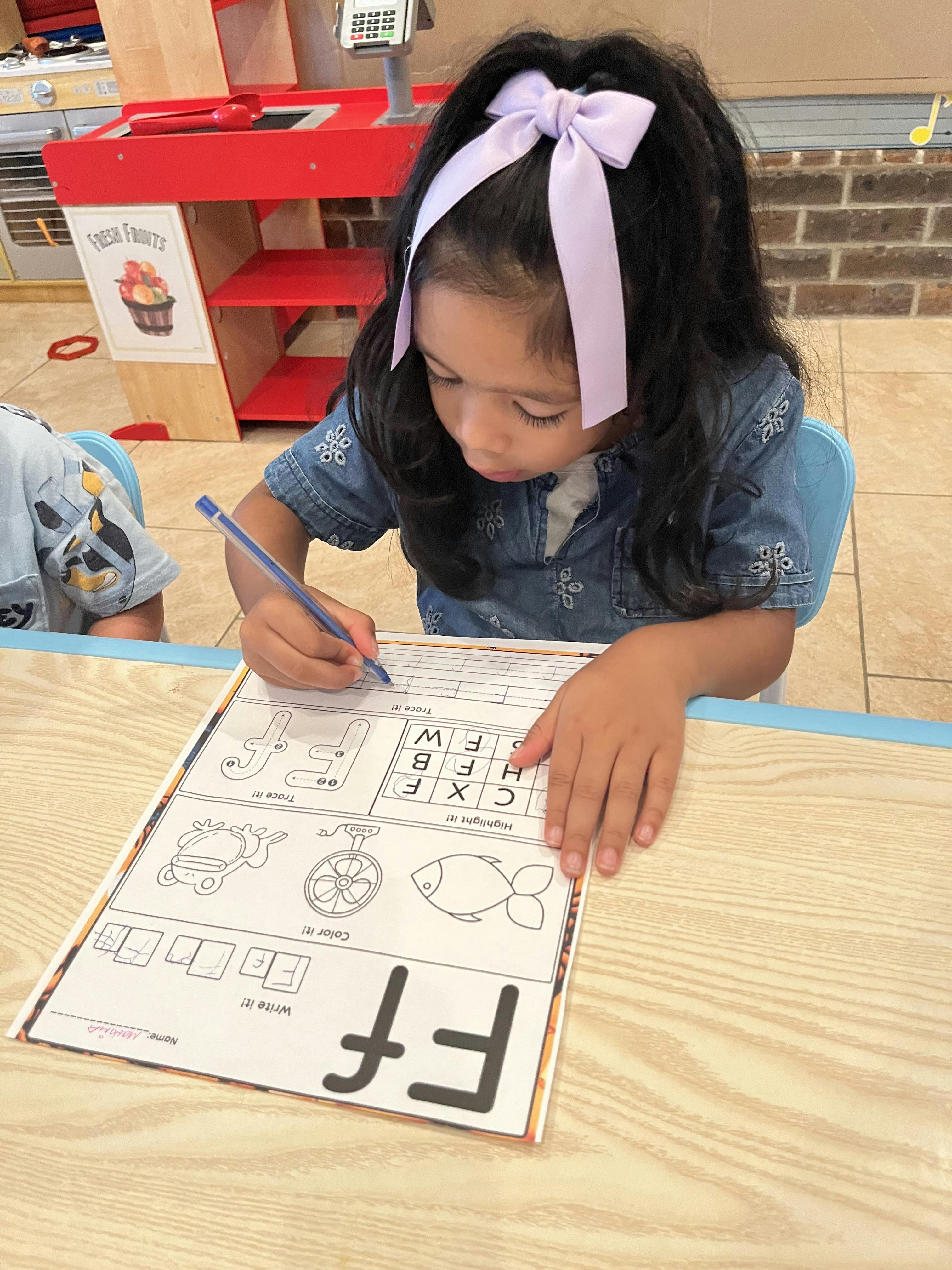 Child writing on a worksheet with the letter F