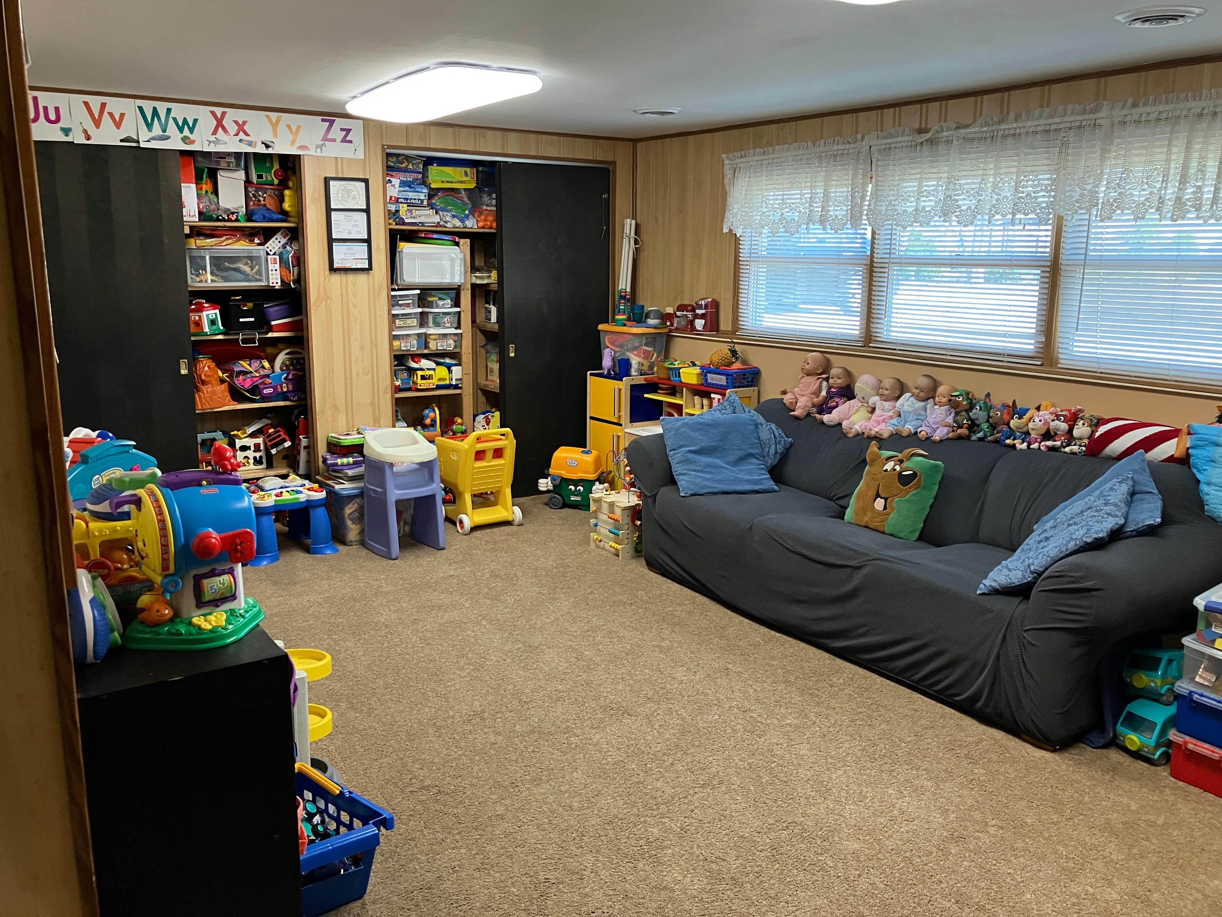 Playroom with a sofa, shelves of toys, and various children's play items
