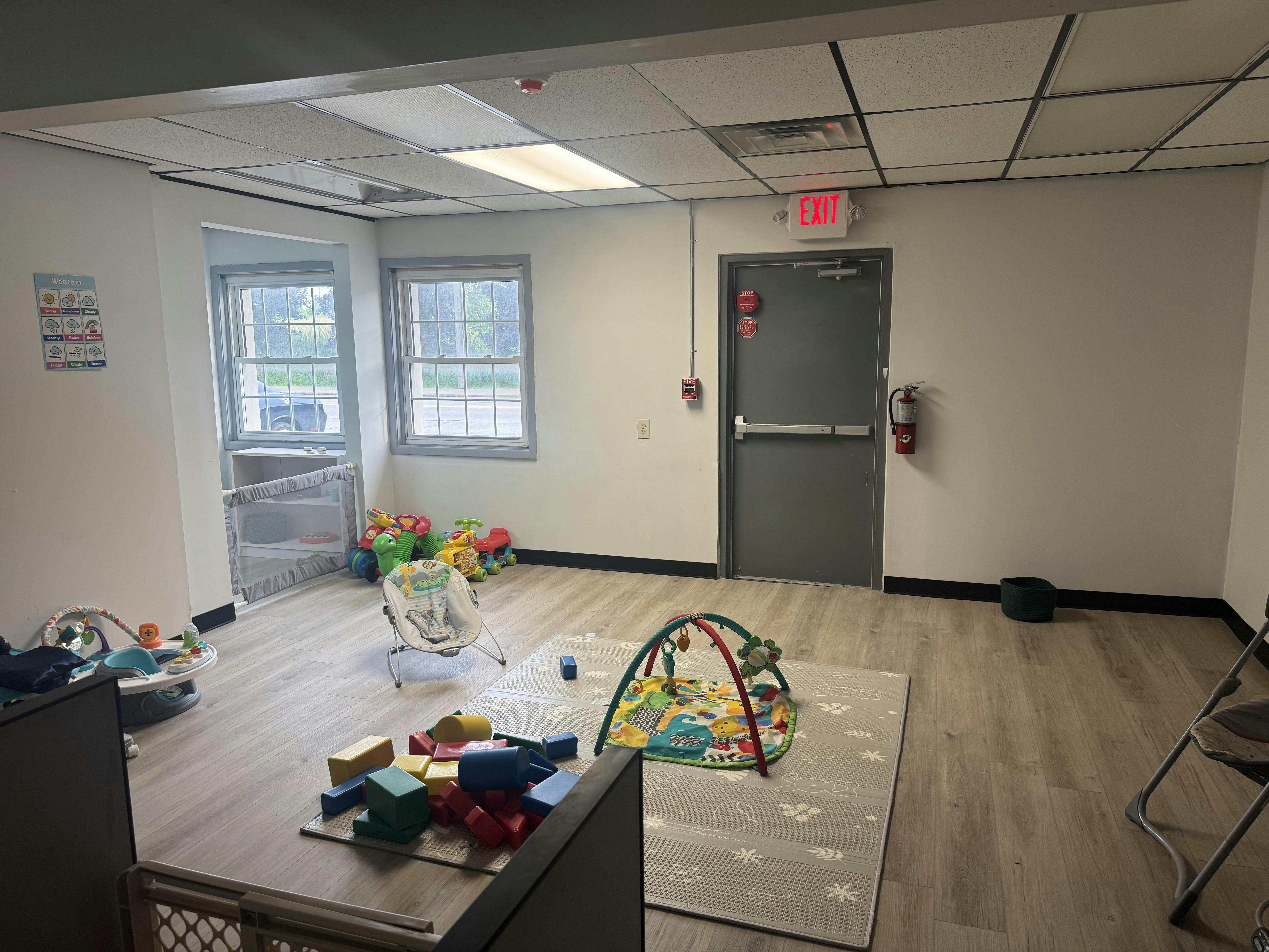 Childcare room with play mats, toys, and an exit door