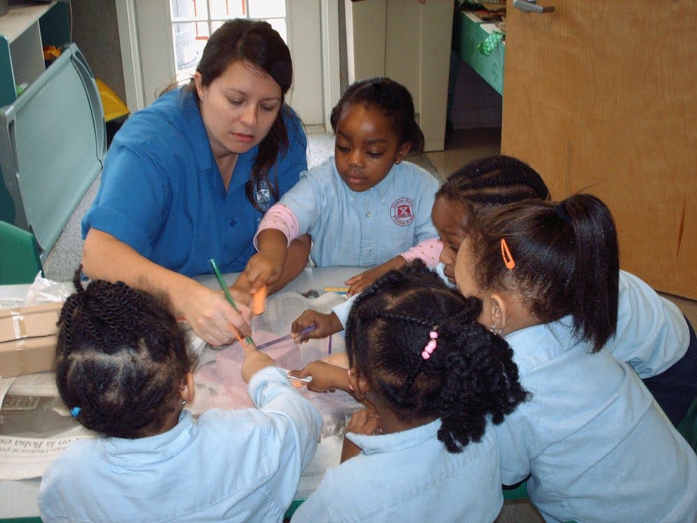 Adult and multiple children gathered around a table, engaged in an activity