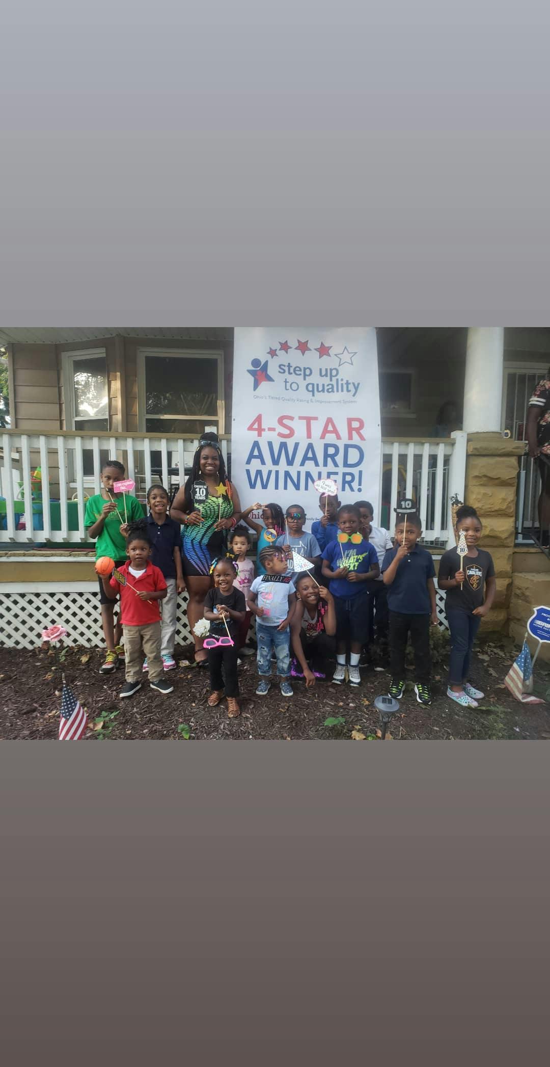 Adult and group of children posing in front of a banner that reads "4-STAR AWARD WINNER!"
