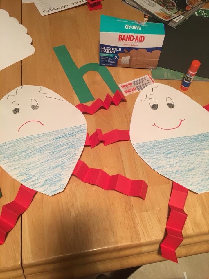 Two paper egg cutouts with drawn faces and red accordion-folded paper limbs
