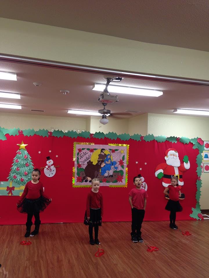 Four children standing on a stage with Christmas decorations