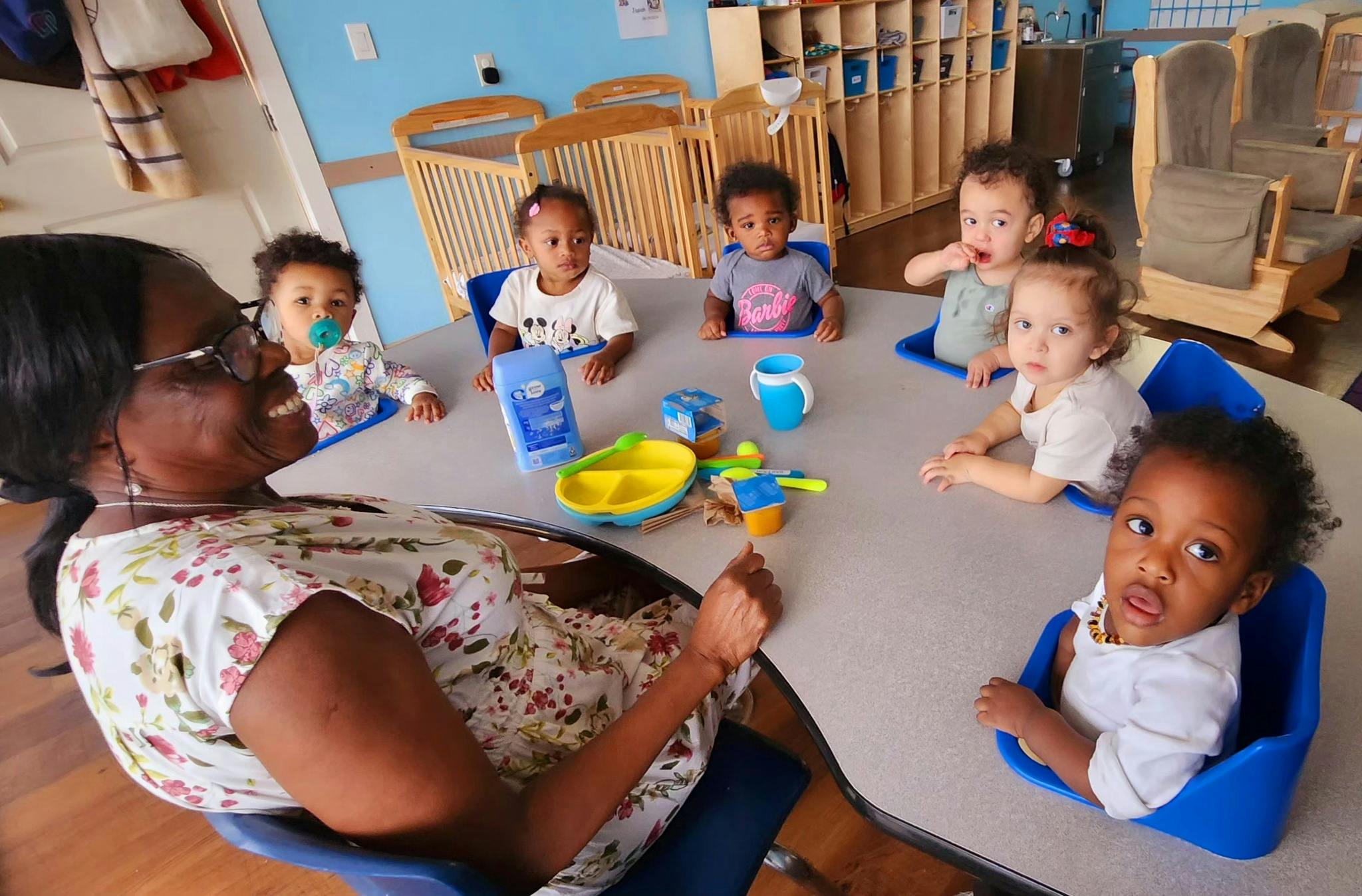 Adult and multiple children sitting around a table with baby items