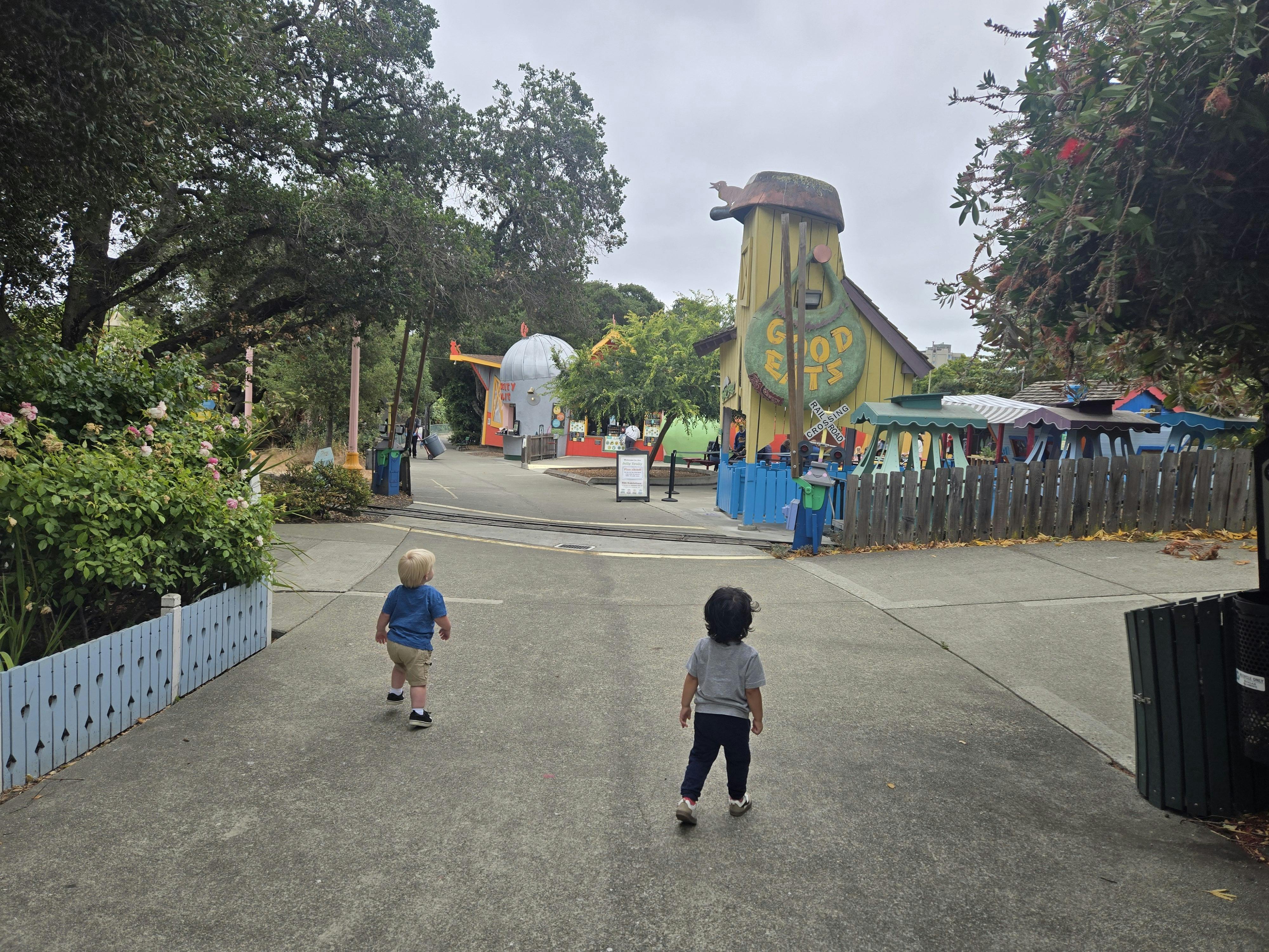 Two children walking on a path towards amusement park rides
