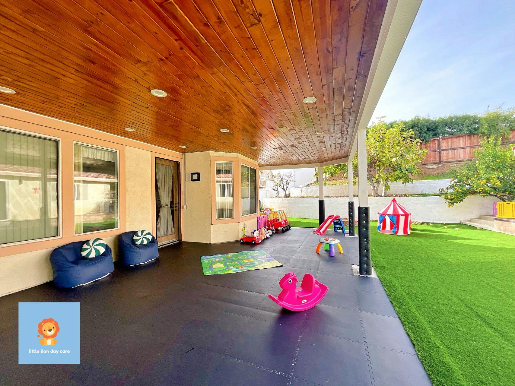 Outdoor play area with covered patio, artificial grass, and children's toys