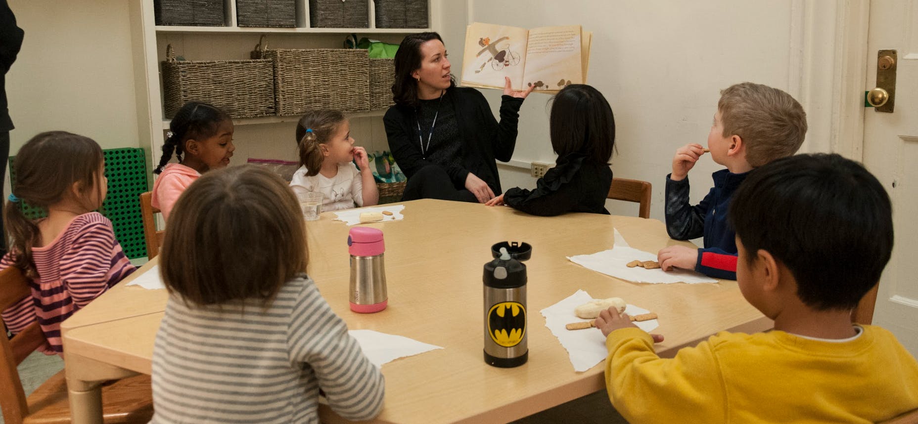 Adult reading a book to children seated around a table