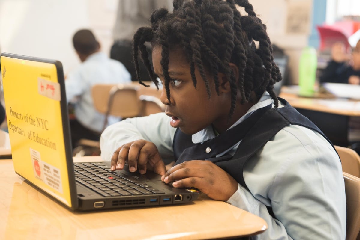Child typing on a laptop in a classroom